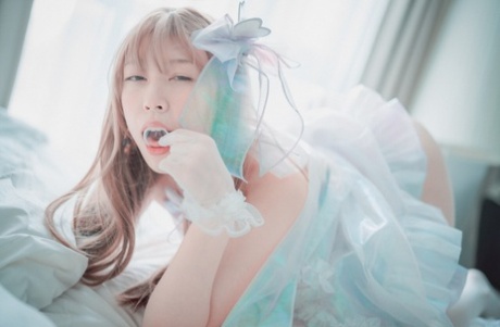 Saucy South Korean girl posing seductively in her white dress and stockings