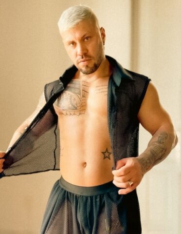 Male bodybuilder with short blonde hair displays his chiseled torso