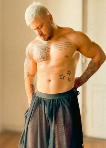 Male bodybuilder with short blonde hair displays his chiseled torso