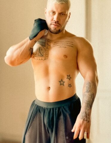 Male bodybuilder with short blonde hair displays his chiseled torso