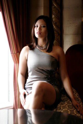 Breathtaking Asian teen Zoey Jones posing in her sexy dress on the sofa