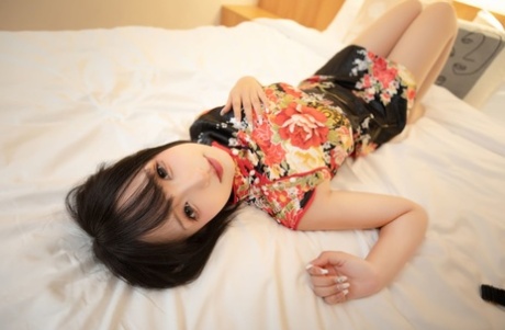 Asian wife sex doll shows her feet and flashes her upskirt on her bed